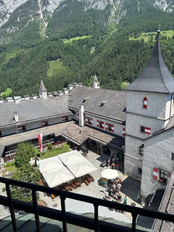 Hohenwerfen Castle in Austria sits among green mountains with a courtyard below.