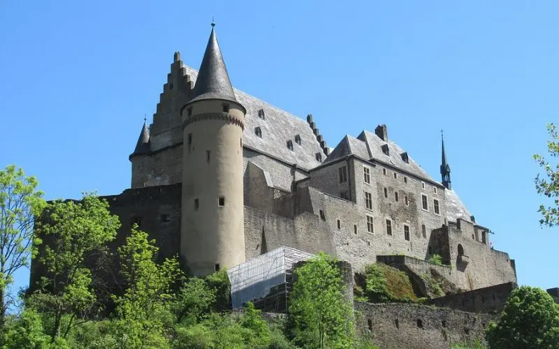Vianden Castle in Luxembourg has stone towers and steep rooftops on a hill.