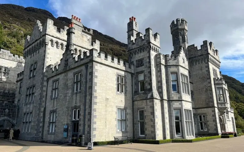 Kylemore Abbey in Ireland is a gray stone castle set against green hills.