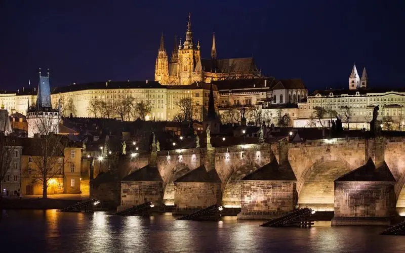 Prague Castle in the Czech Republic glows above the city at night with lights.