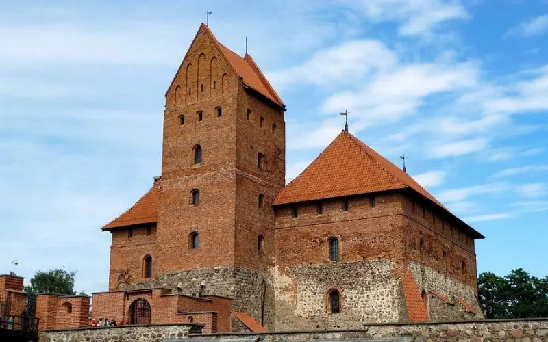 Trakai Island Castle in Lithuania made of red brick with pointed roofs and towers.
