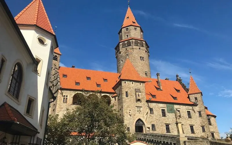 Bouzov Castle in the Czech Republic with red rooftops and a tall central tower.