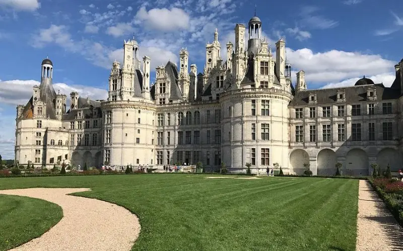 Château de Chambord in France displays ornate white towers and a wide green lawn.