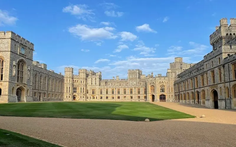 Windsor Castle in England surrounds a large courtyard with stone walls and towers.