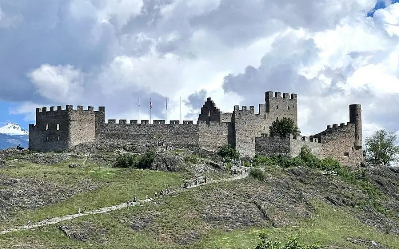 Tourbillon Castle in Switzerland is perched on a hilltop with stone walls and towers.