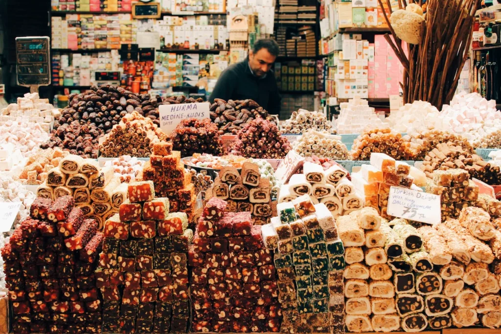 Market stall displaying Turkish delight, dried dates, and other sweets with a shopkeeper behind the counter