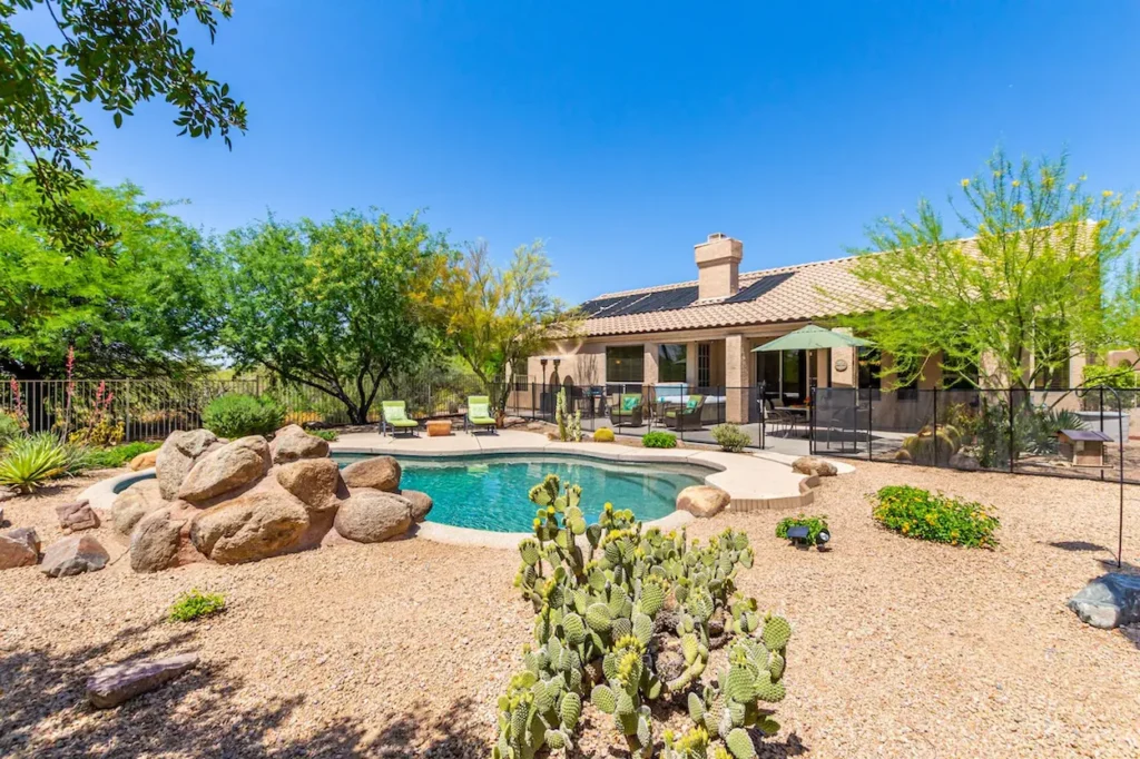 Inground swimming pool with a rock feature and prickly pear cactus in a gravel backyard