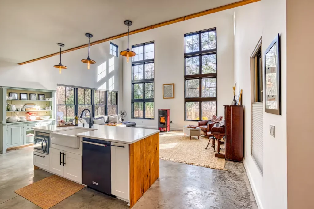 Modern open-concept home with a kitchen island, concrete floors, and double-height windows