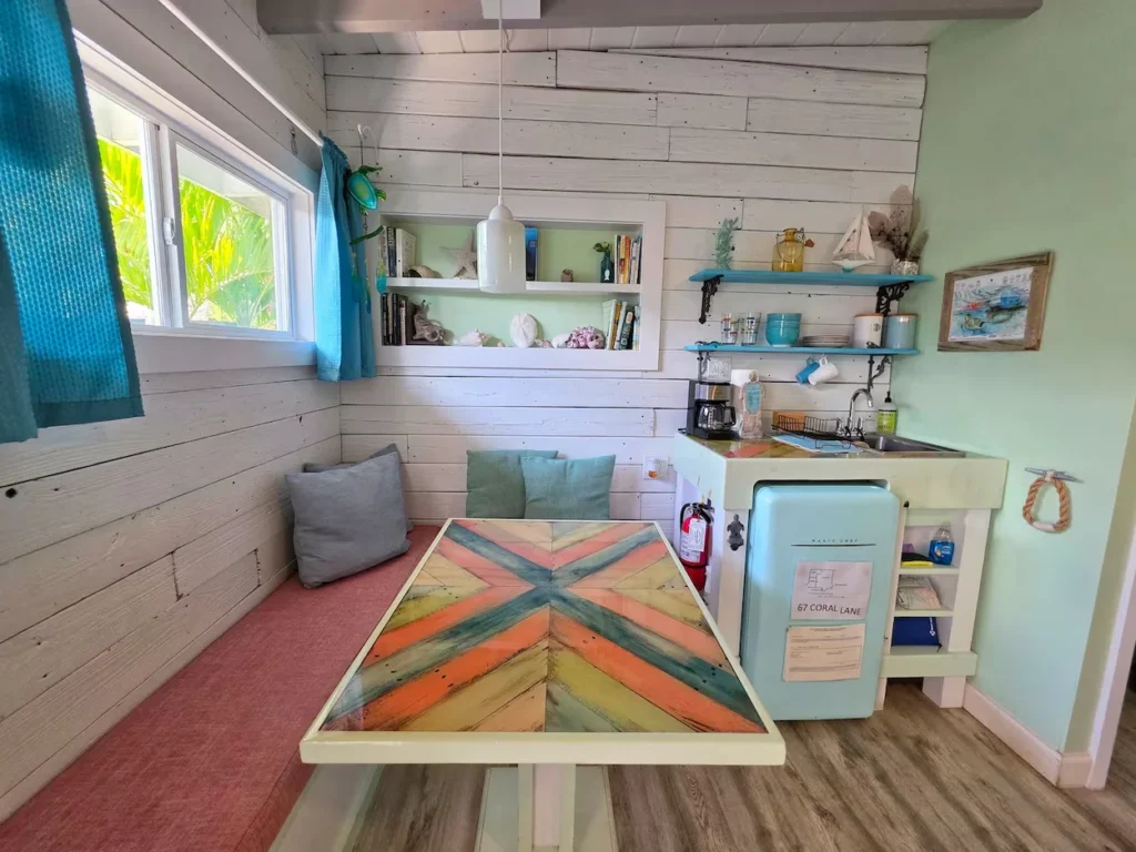 Beach cottage kitchenette and a built-in dining booth with a colorful geometric table