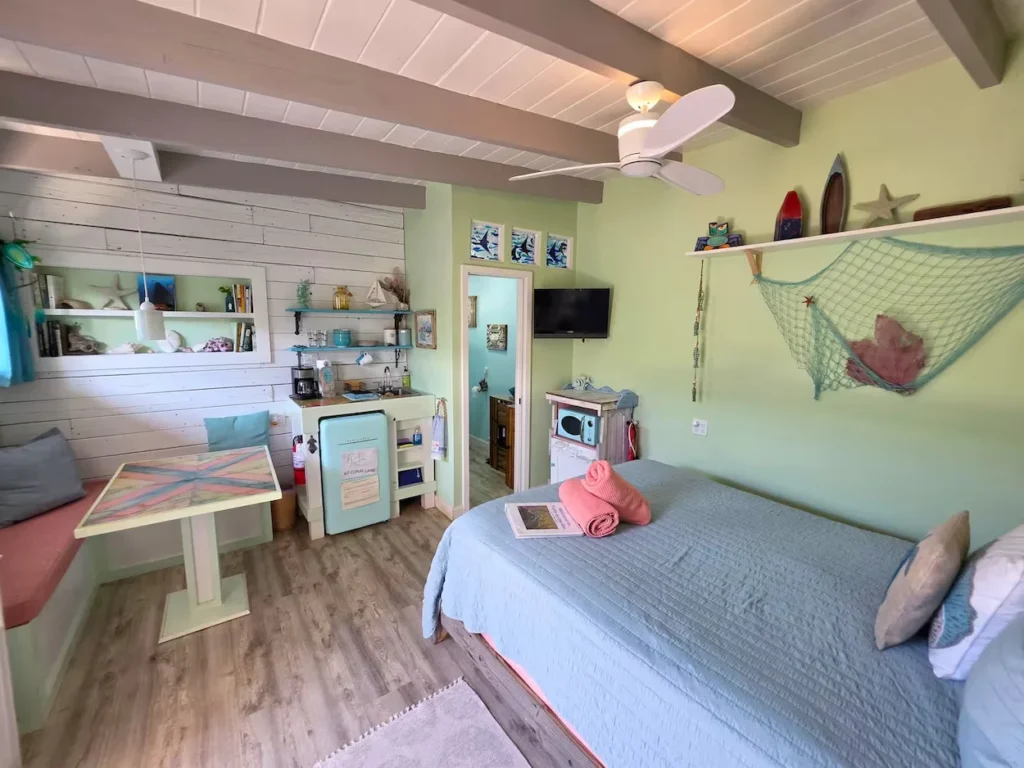 Cozy beach cottage studio with a bed, a small dining table, and green walls