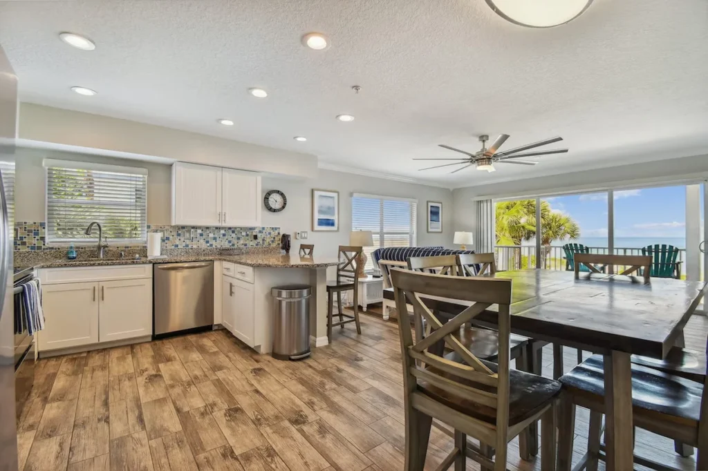 An open kitchen with white cabinets and granite countertops next to a wooden dining table setup