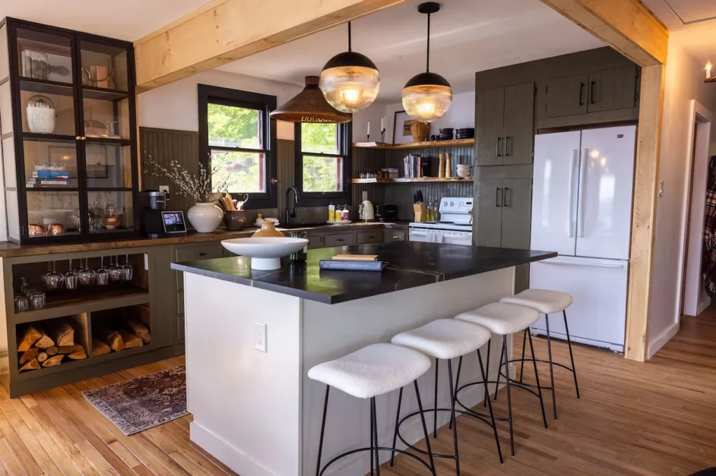 Modern kitchen with dark countertops, white bar stools, and globe pendant lights