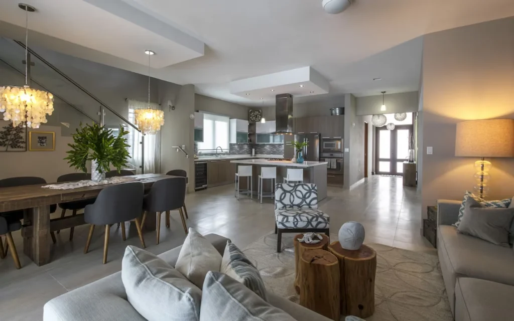 Open concept villa interior showing a living room with couches, a dining table, and a modern kitchen in the background