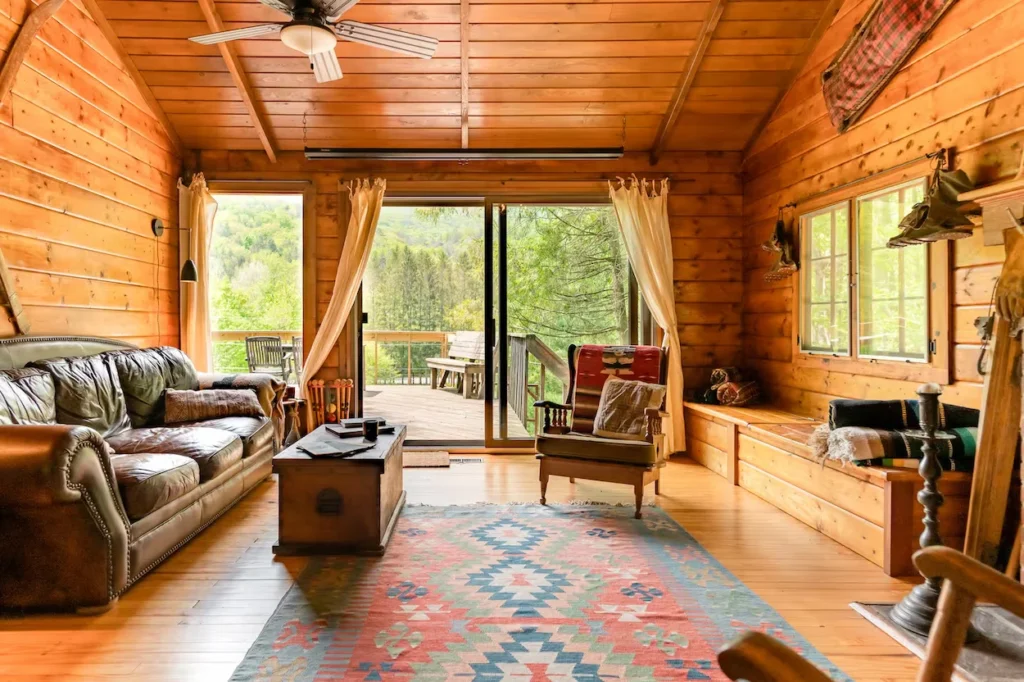 Rustic wood cabin living room with a brown leather couch and a patterned rug
