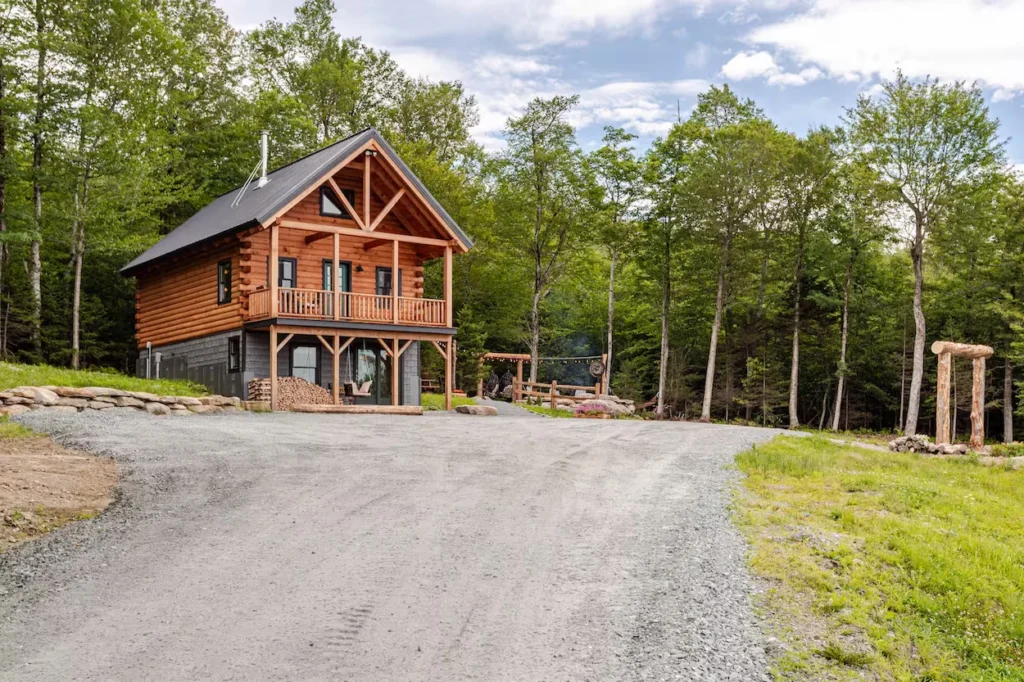 Two-story log cabin with a balcony next to a forest