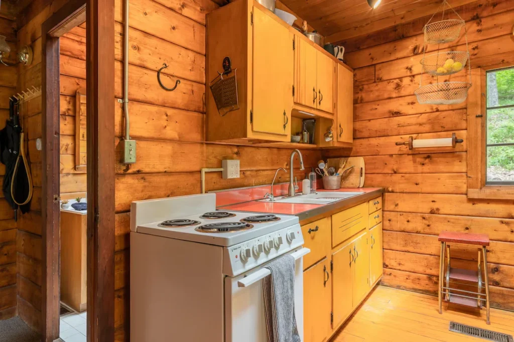 Rustic wood cabin kitchen with yellow cabinets and a white stove
