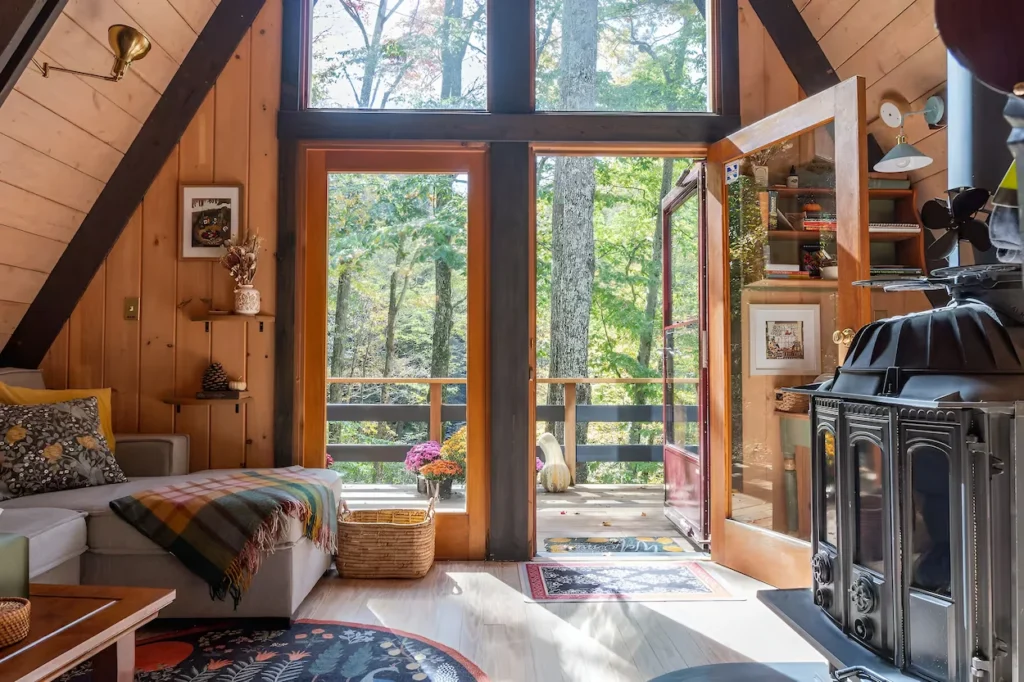 Cozy A-frame cabin living room featuring wood walls, a sectional couch, and a vintage black wood stove