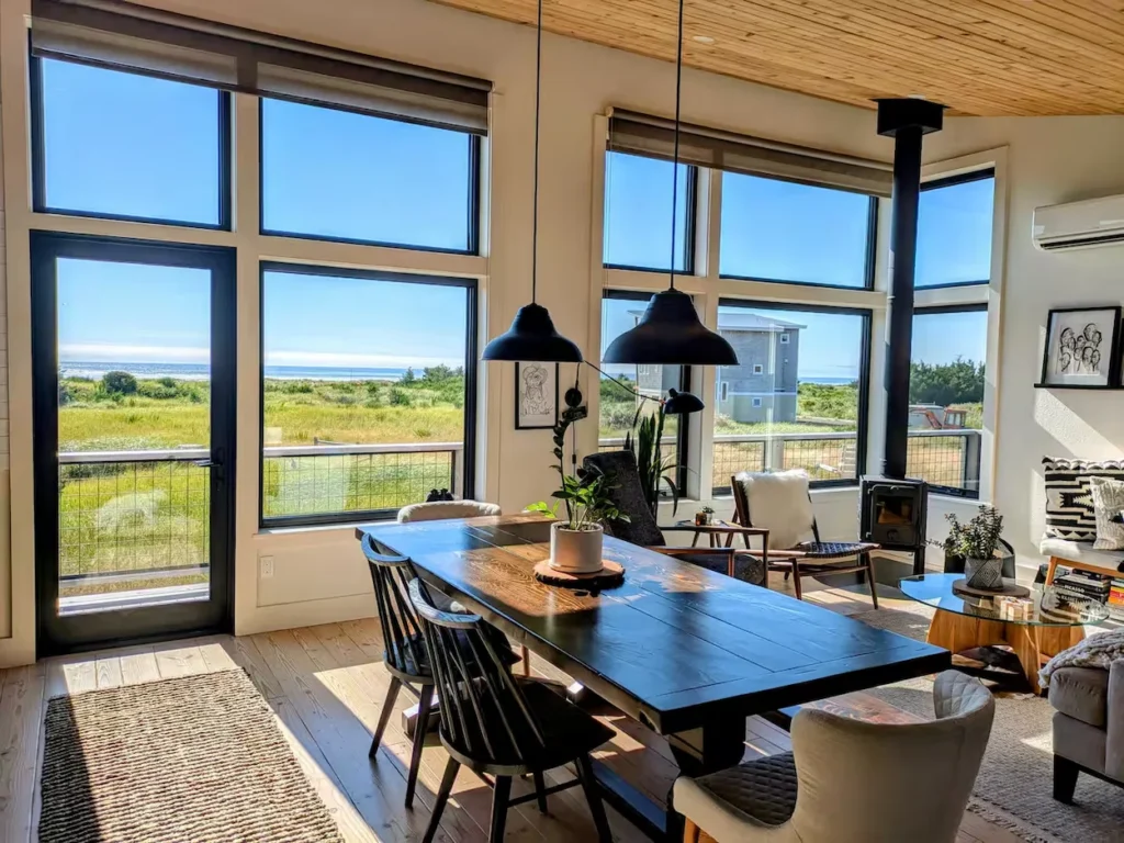 Modern dining room with a wooden table and large windows showing a beach view