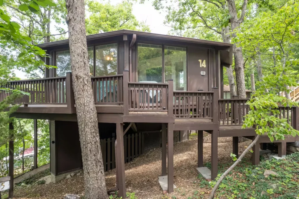 Brown wooden octagonal cottage with a large deck numbered fourteen in the woods