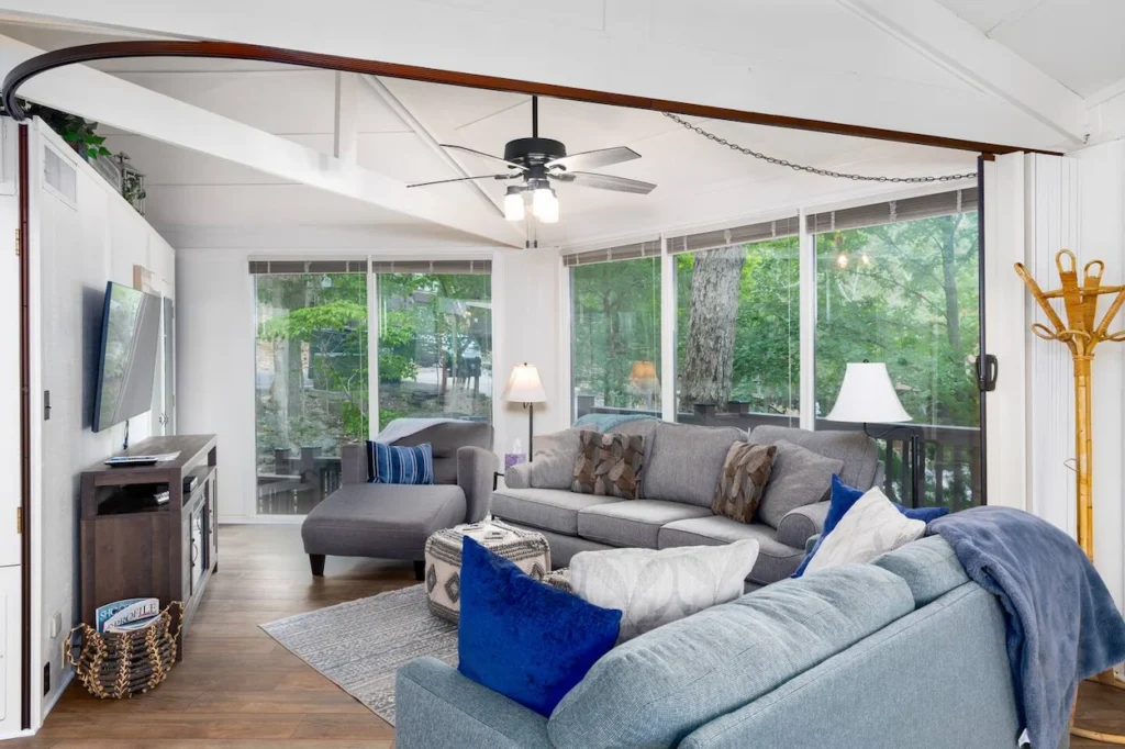 Bright cottage living room with blue and grey sofas and wall-to-wall windows