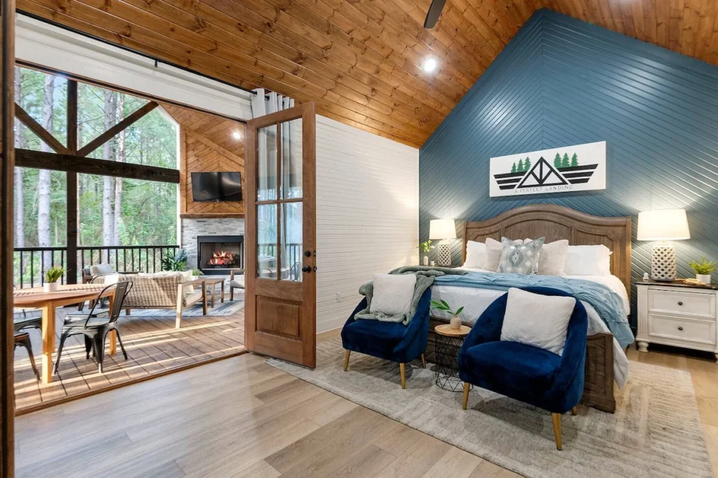 Luxury cabin bedroom with a blue accent wall, wooden bed frame, and open doors leading to a patio