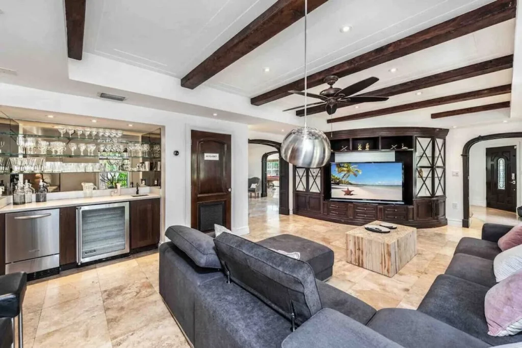 Modern living room with a large dark wood entertainment center, gray sectional sofa, and a built-in wet bar