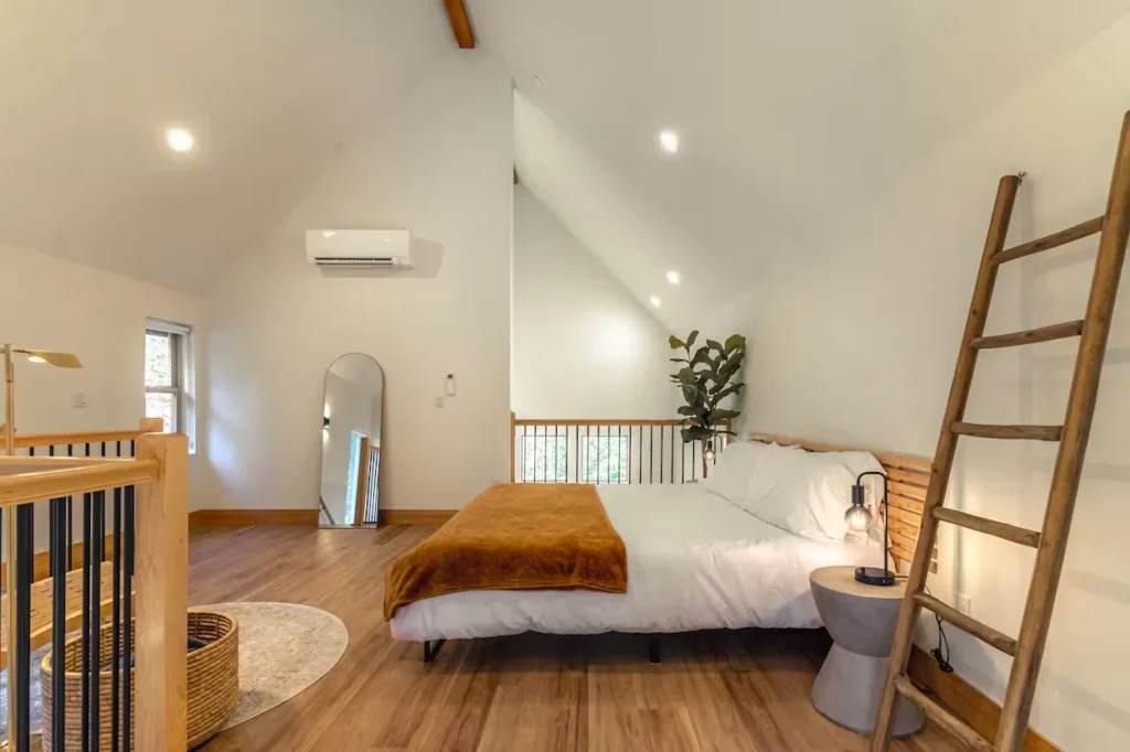 Loft bedroom with a king bed, white bedding, vaulted ceiling, and wooden floors