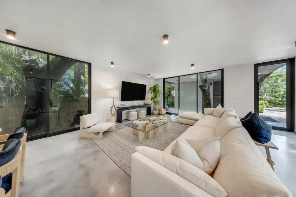 Minimalist living room with polished concrete floors, large white sectional, and floor-to-ceiling glass walls
