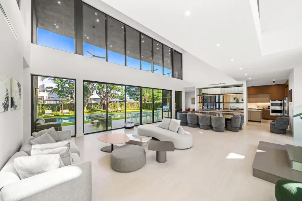Bright modern mansion great room with towering windows overlooking a pool backyard