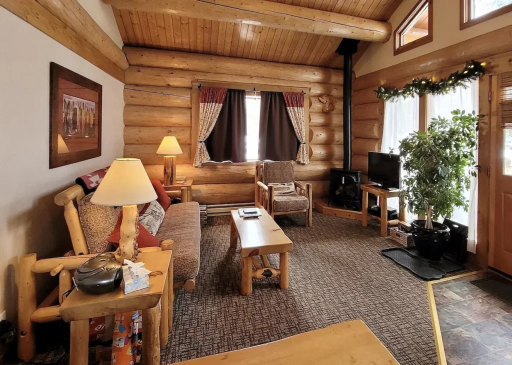 Cozy log cabin living room with log furniture, a wood stove, and wood-paneled walls