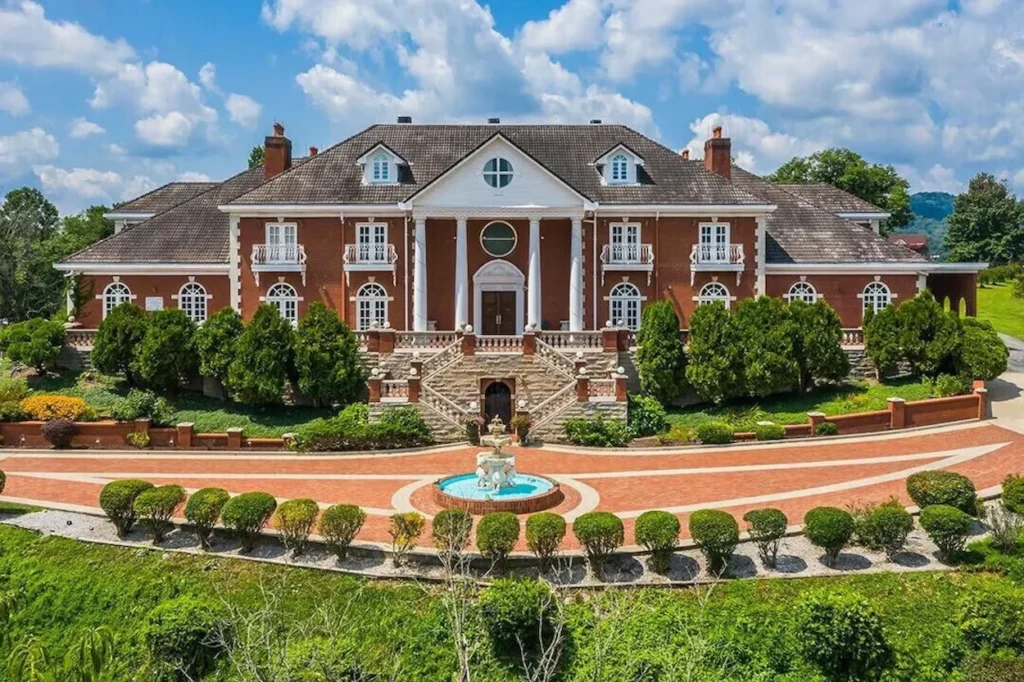 Large red brick mansion with a fountain and circular driveway