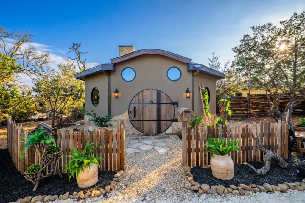 Hobbit style cottage with a round wooden front door and a picket fence