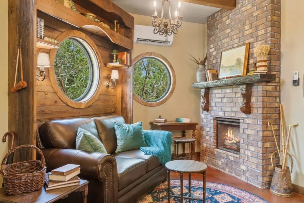 Cozy living room with round windows, a leather sofa, and a brick fireplace