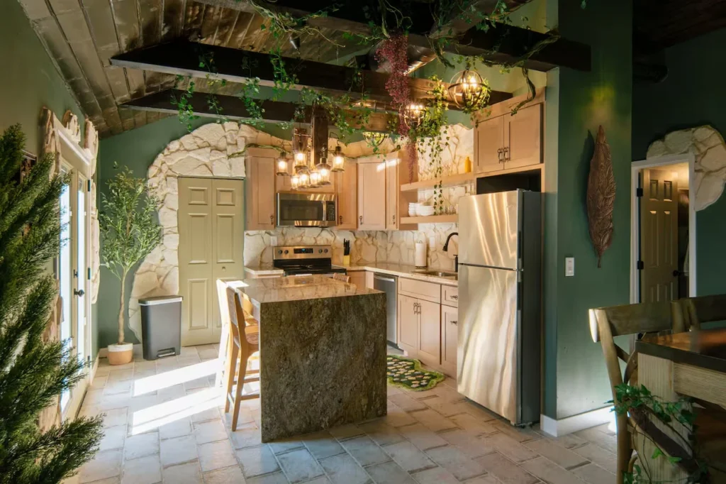 Hobbit themed kitchen with stone wall accents, green walls, a granite island, and hanging ceiling vines