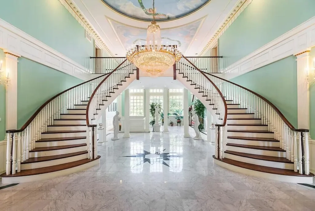 Mansion grand foyer with twin curved staircases and a crystal chandelier