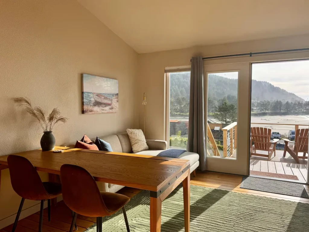 Studio with dining table and glass doors opening to a balcony facing the beach