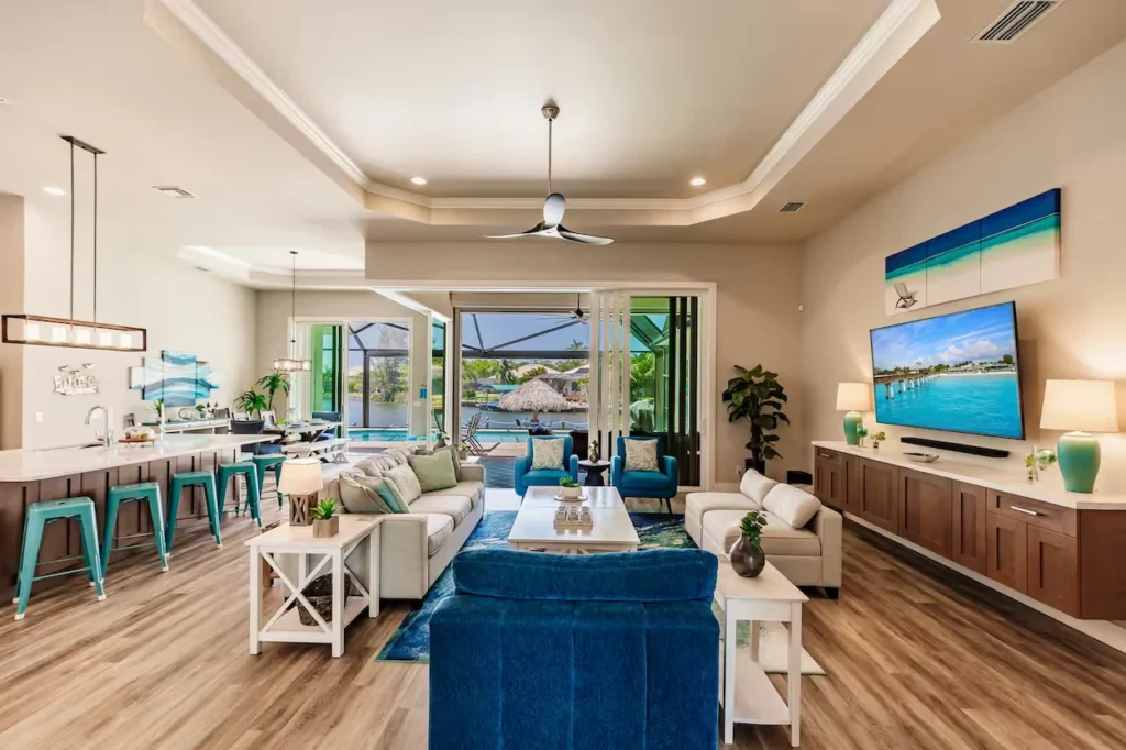 Spacious living room featuring teal and blue furniture, tray ceiling, kitchen island, and glass doors to an outdoor patio