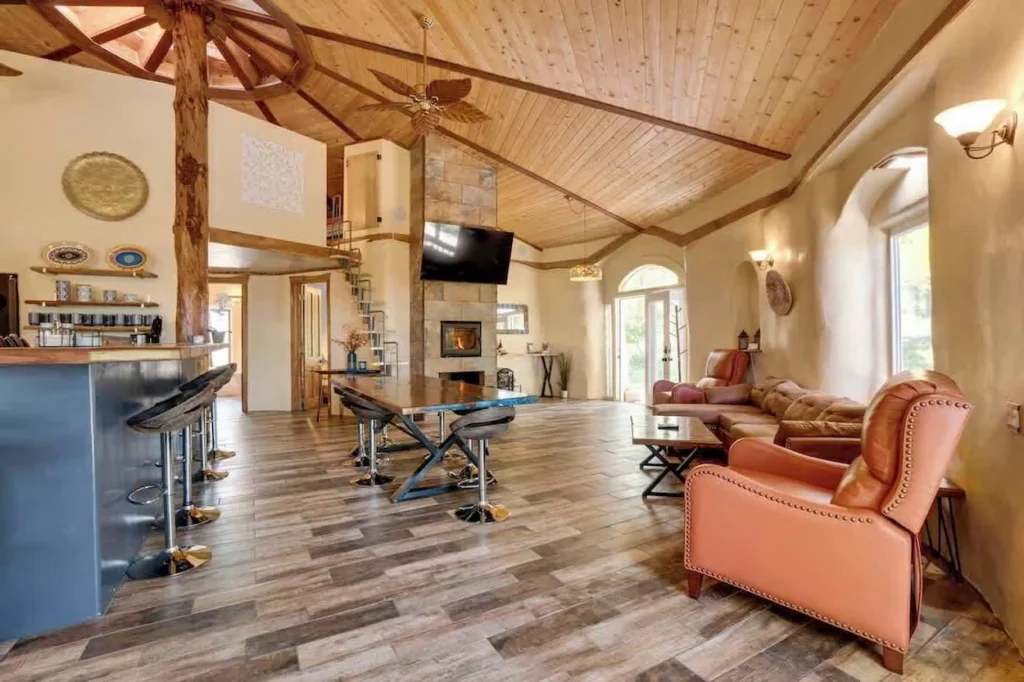 Spacious open-concept living area with earth walls, a wood ceiling, a fireplace, and a bar counter