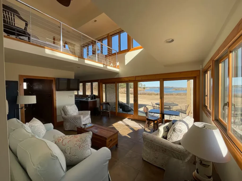 Cabin living room with glass doors opening to a yard facing the river
