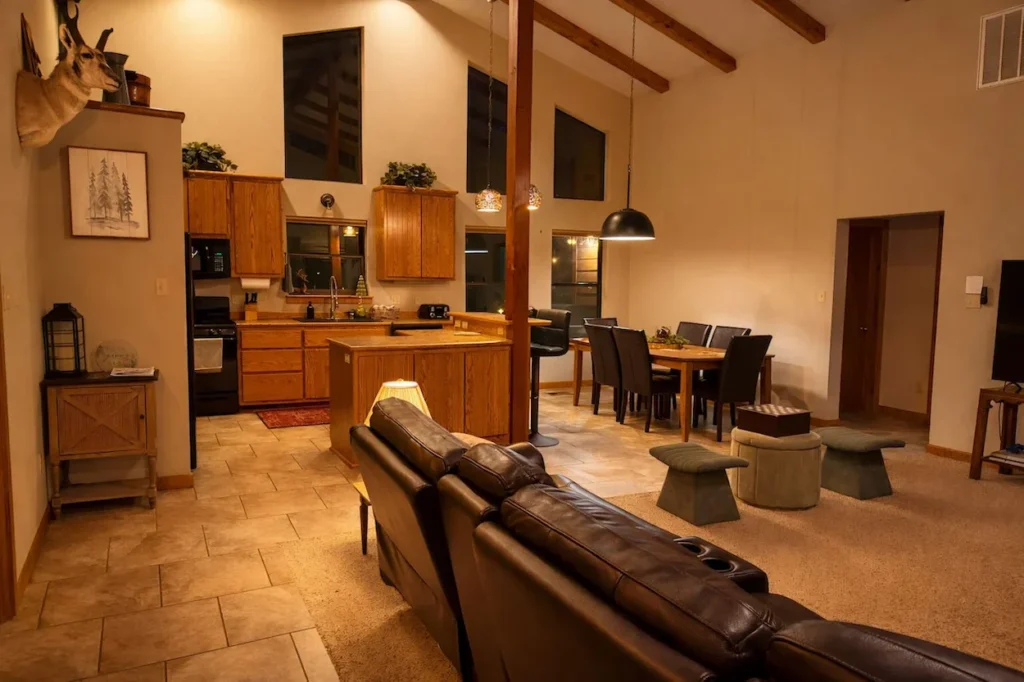 An open-concept cabin living room leading into a wooden kitchen with tile flooring