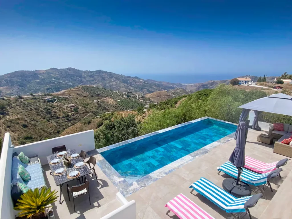Spain villa patio with an infinity pool and dining table overlooking mountains