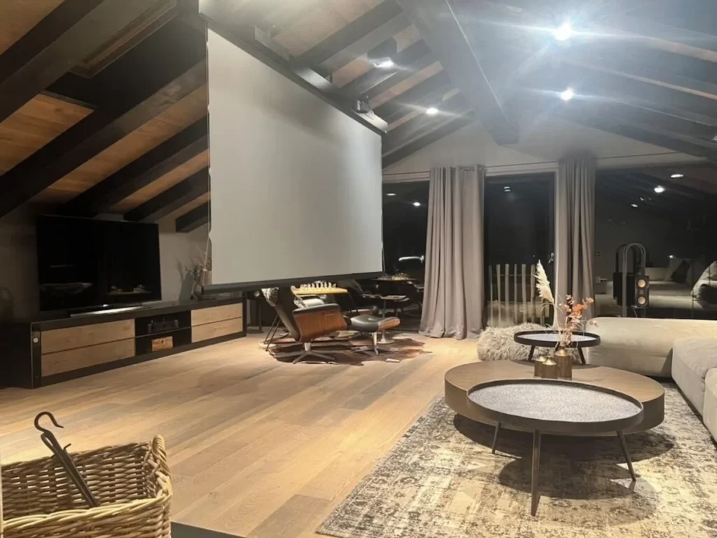 Luxury chalet home theater with a large projection screen, vaulted wood ceilings, and modern seating