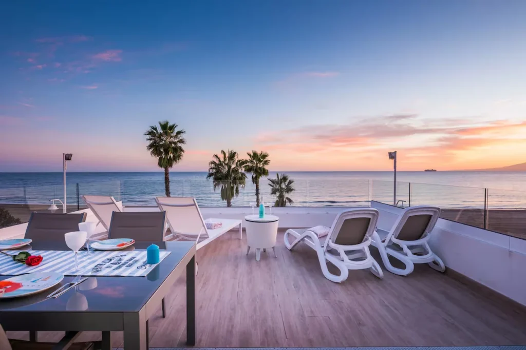 Beachfront villa terrace in Malaga with lounge chairs overlooking the ocean at sunset