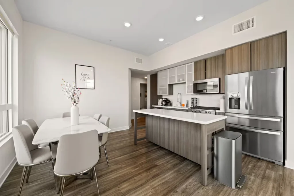 Modern penthouse kitchen with wood cabinets, center island, and white dining table