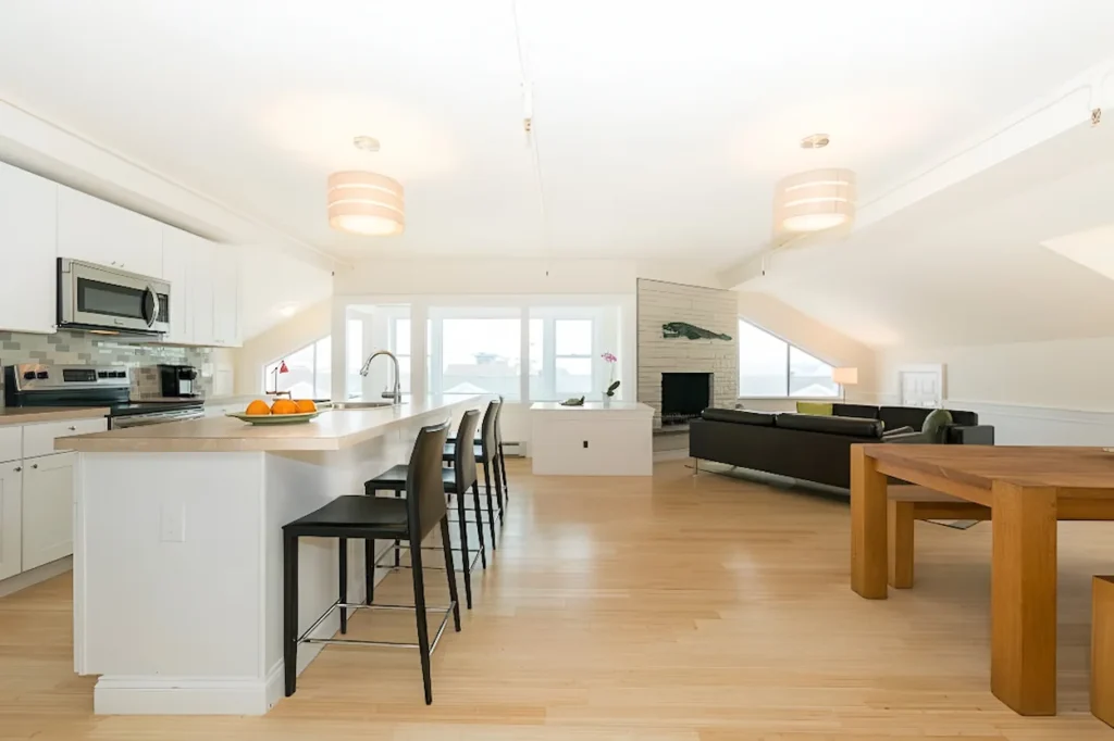 Open-concept penthouse interior featuring a white kitchen island, living room area, and wood floors