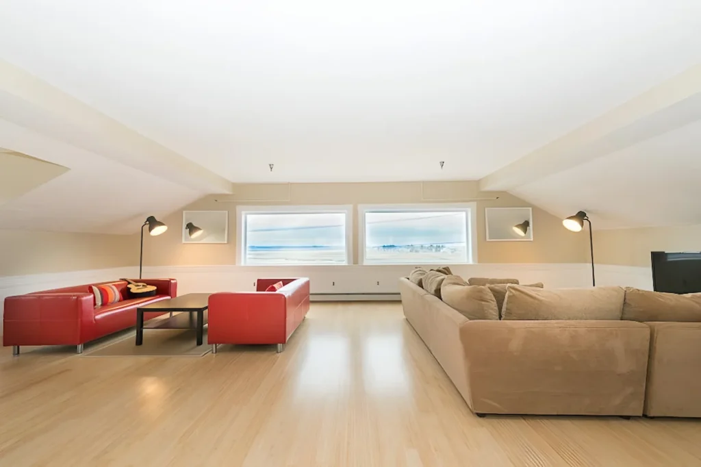 Spacious loft living room with sloped ceilings, two red couches, and a large beige sectional