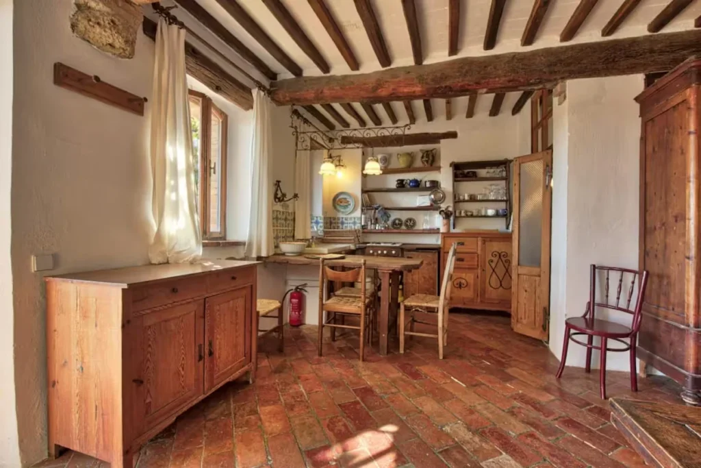 Rustic villa interior with terracotta tile flooring, exposed wood ceiling beams, and vintage wooden furniture