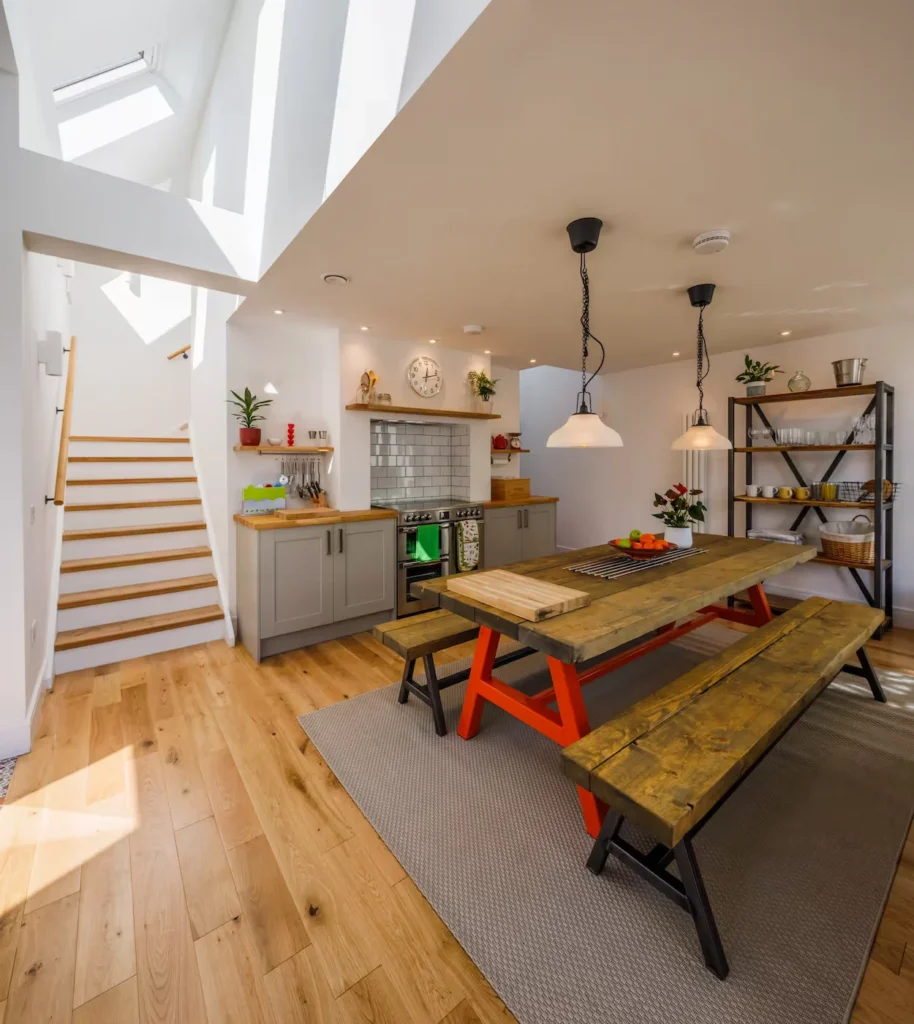 Modern open-concept kitchen with a large wooden picnic-style dining table and skylights