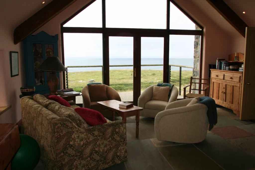 Cozy cabin living room with armchairs facing a large window with sea views
