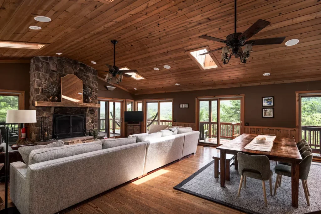 Cabin great room with a stone fireplace, large sectional sofa, and wooden dining set